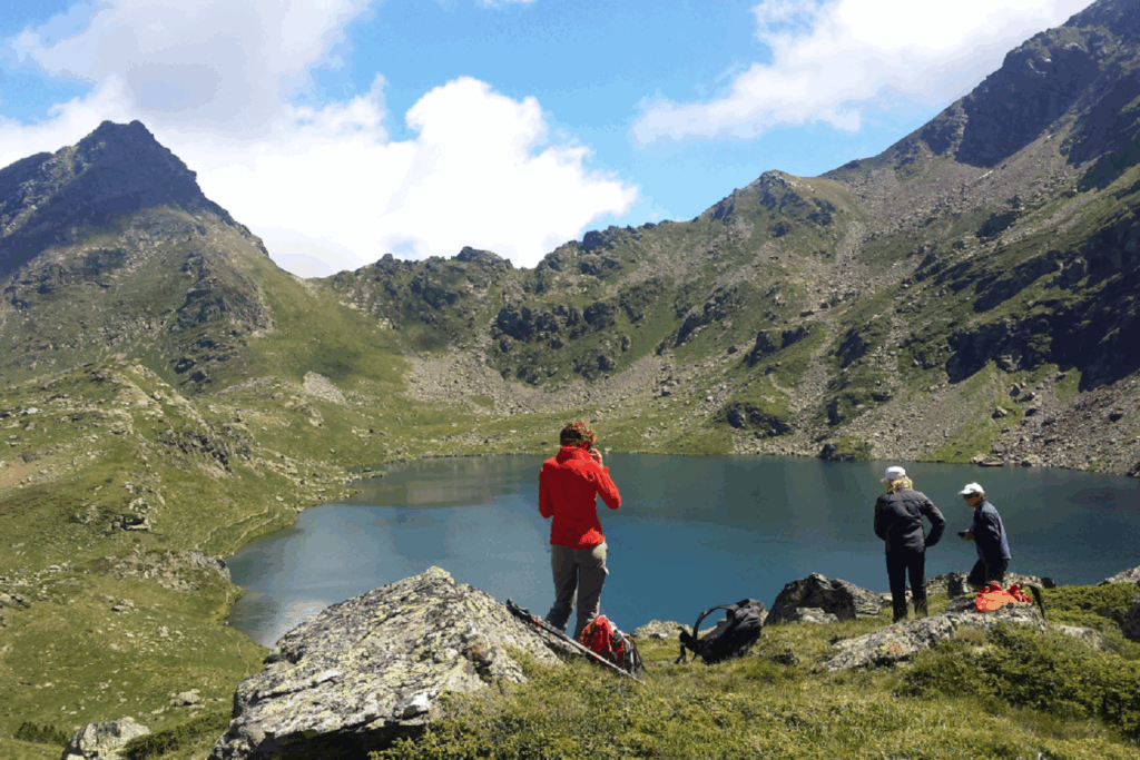 Groupe de randonneurs en contrebas d'un lac de montagne encadré de sommets