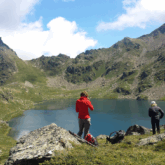 Groupe de randonneurs en contrebas d'un lac de montagne encadré de sommets