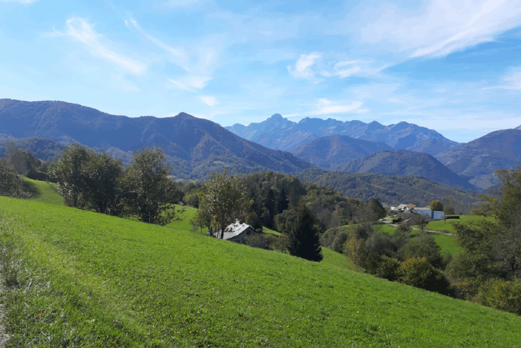 Paysage de montagne avec des sommets et des reliefs, et au premier plan une plaine verte due à la saison estivale