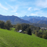 Paysage de montagne avec des sommets et des reliefs, et au premier plan une plaine verte due à la saison estivale
