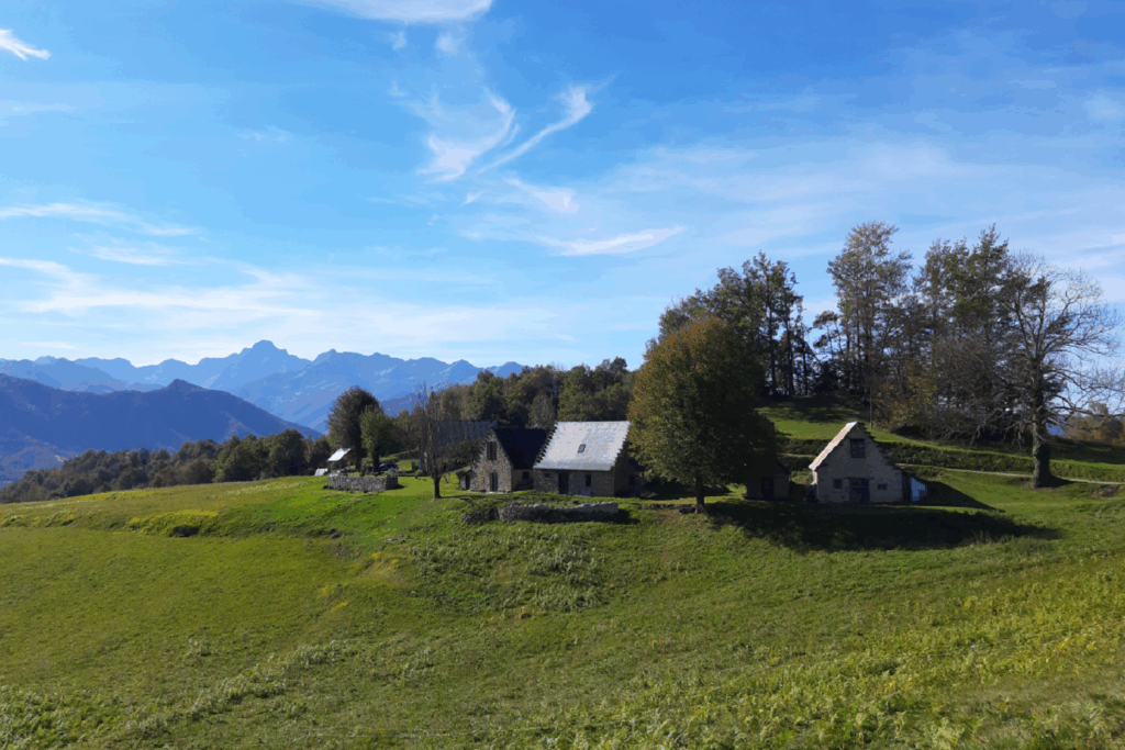 Paysage de montagne avec des petites maisons en fond, avec à l'arrière-plan des montagnes