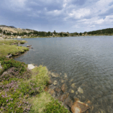 Paysage de montagne avec un lac au centre de l'image encadré de végétation