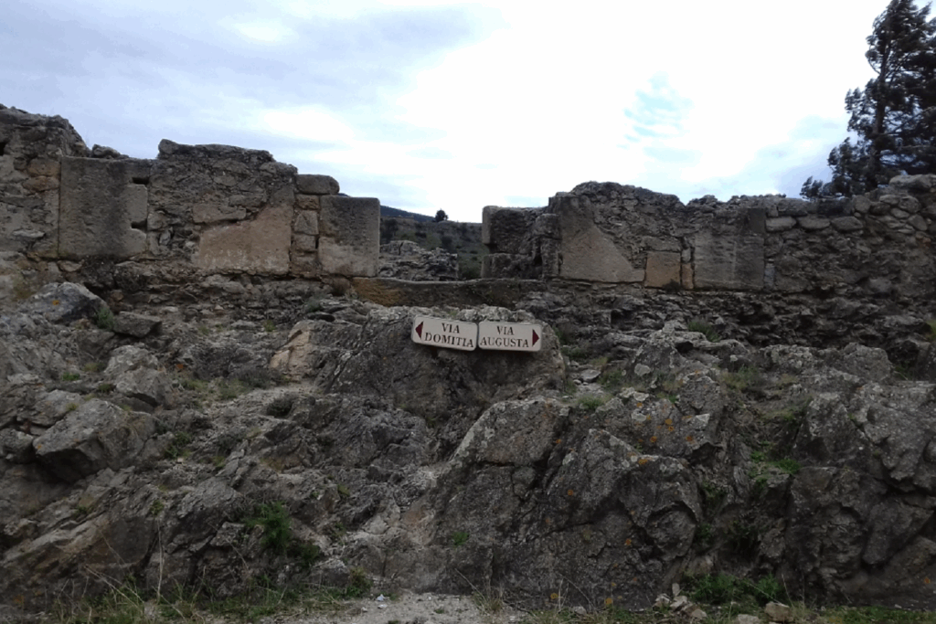 Paysage montagnard avec un mur de pierre et des panneaux indicateurs de sentiers