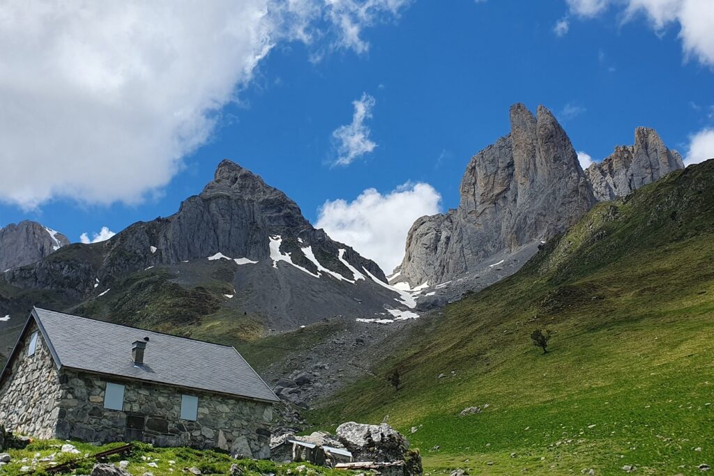 Paysage de montagne avec deux sommets et au pied de ces sommets une maison en pierre