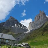 Paysage de montagne avec deux sommets et au pied de ces sommets une maison en pierre