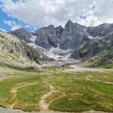 Paysage de montagne avec le Vignemale en fond, une grande plaine sur le devant marquée de sentiers.