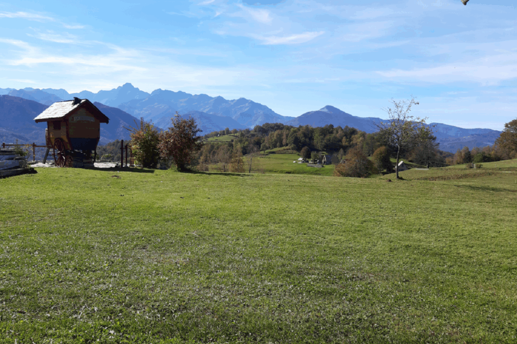 Paysage de montagne avec un plateau ensoleillé et en fond on discerne des sommets