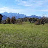 Paysage de montagne avec un plateau ensoleillé et en fond on discerne des sommets