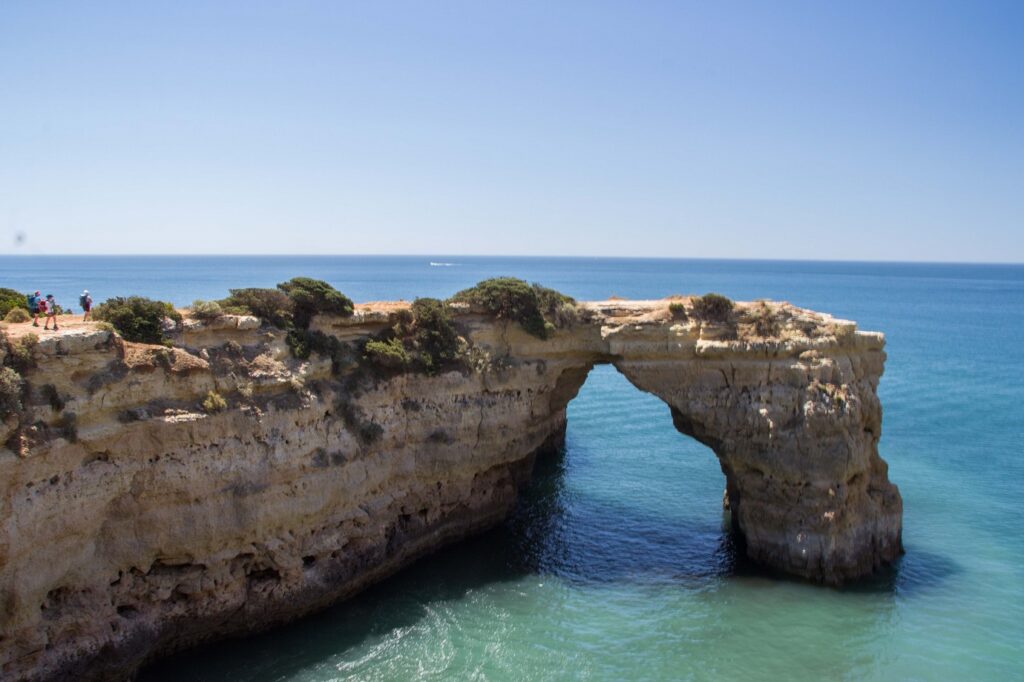 Paysage littoral avec de l'eau aux couleurs turquoises et un pont naturel en pierre passant au-dessus