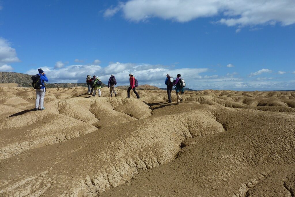 Groupe de randonneurs sur un terrain de Bardenas, sur la terre sèche due au climat, accompagné par leur guide