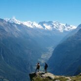 Deux randonneurs sur un rocher face aux différents sommets, face à eux, sur la haute route de Chamonix-Zermatt