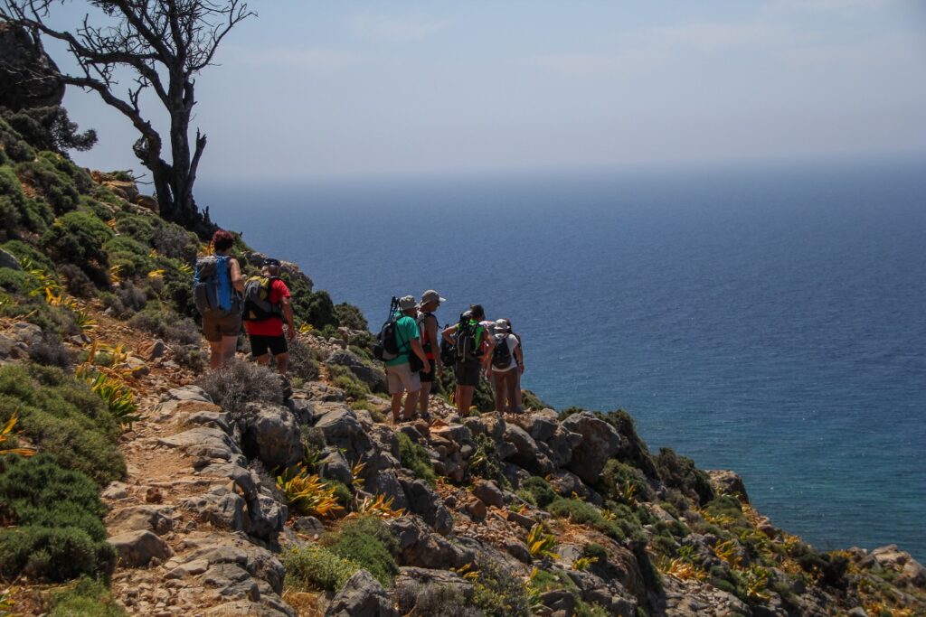 Groupe de randonneurs sur un sentier à flanc de montagne avec la mer en contrebas