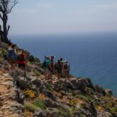 Groupe de randonneurs sur un sentier à flanc de montagne avec la mer en contrebas