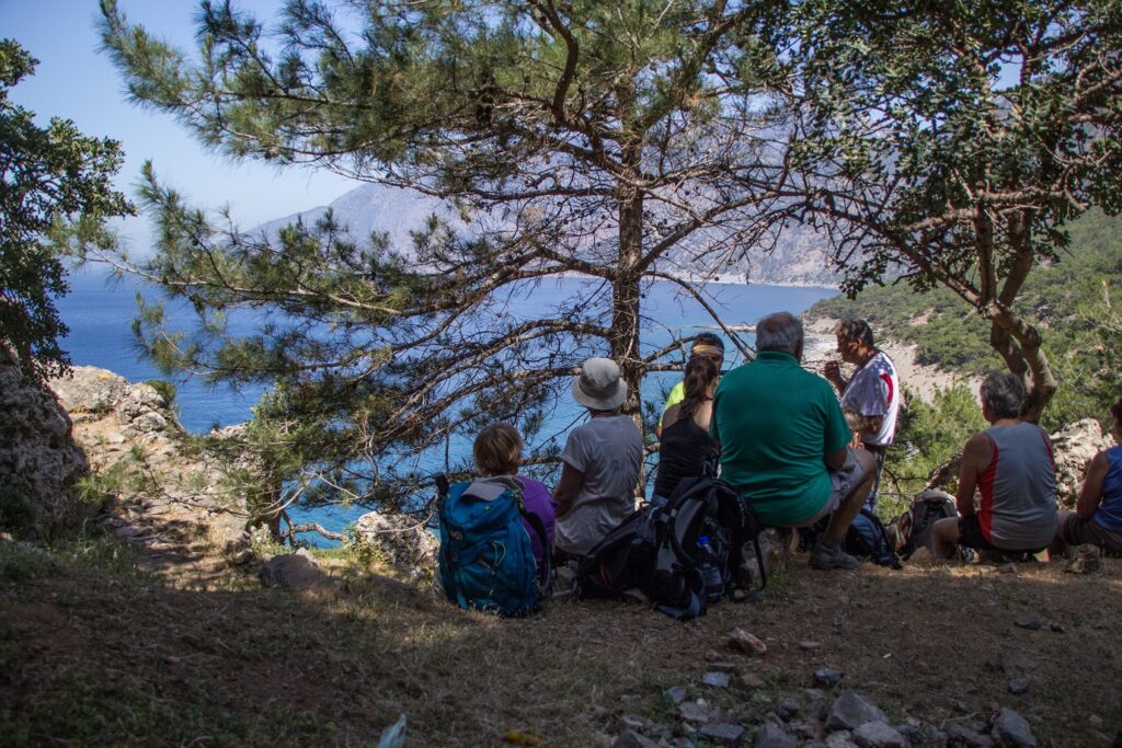 Groupe de randonneurs sur un sentier en train de boire face à la vue de la mer