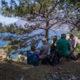 Groupe de randonneurs sur un sentier en train de boire face à la vue de la mer