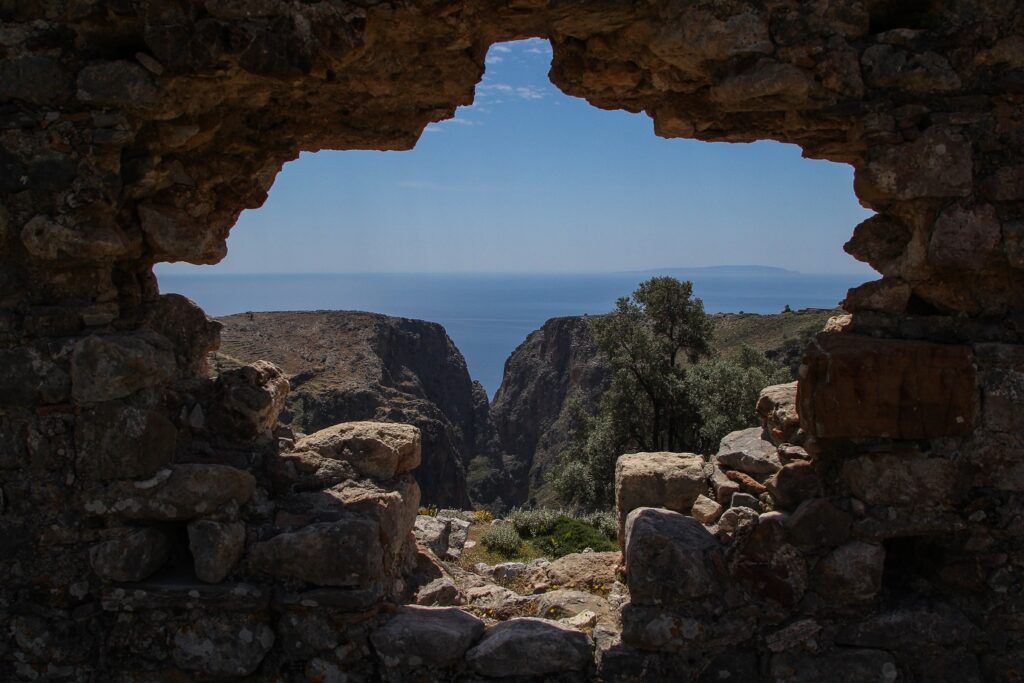 prise de vue à travers un trou dans une construction faite de briques du paysage en Crète, avec en contrebas la mer
