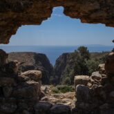 prise de vue à travers un trou dans une construction faite de briques du paysage en Crète, avec en contrebas la mer