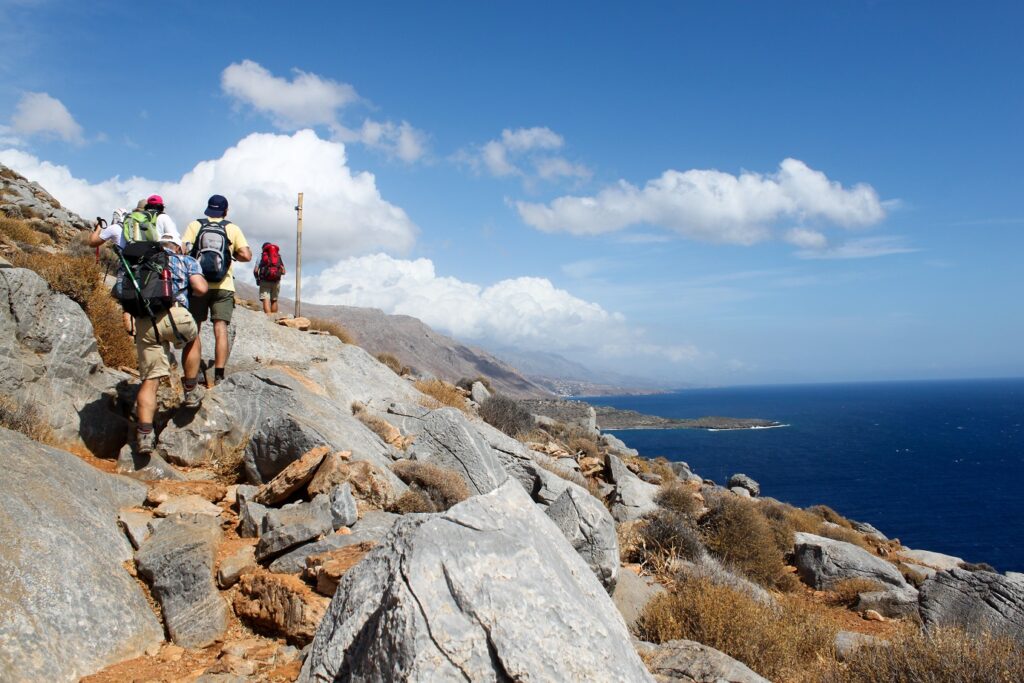 Groupe de randonneurs sur un sentier de montagne avec la mer en contrebas en Crète