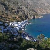 Paysage observé sur l'île de Crète avec une baie formée par les montagnes ainsi qu'un village en contrebas, constitué de maisons blanches, très typique de la Grèce et de ses îles