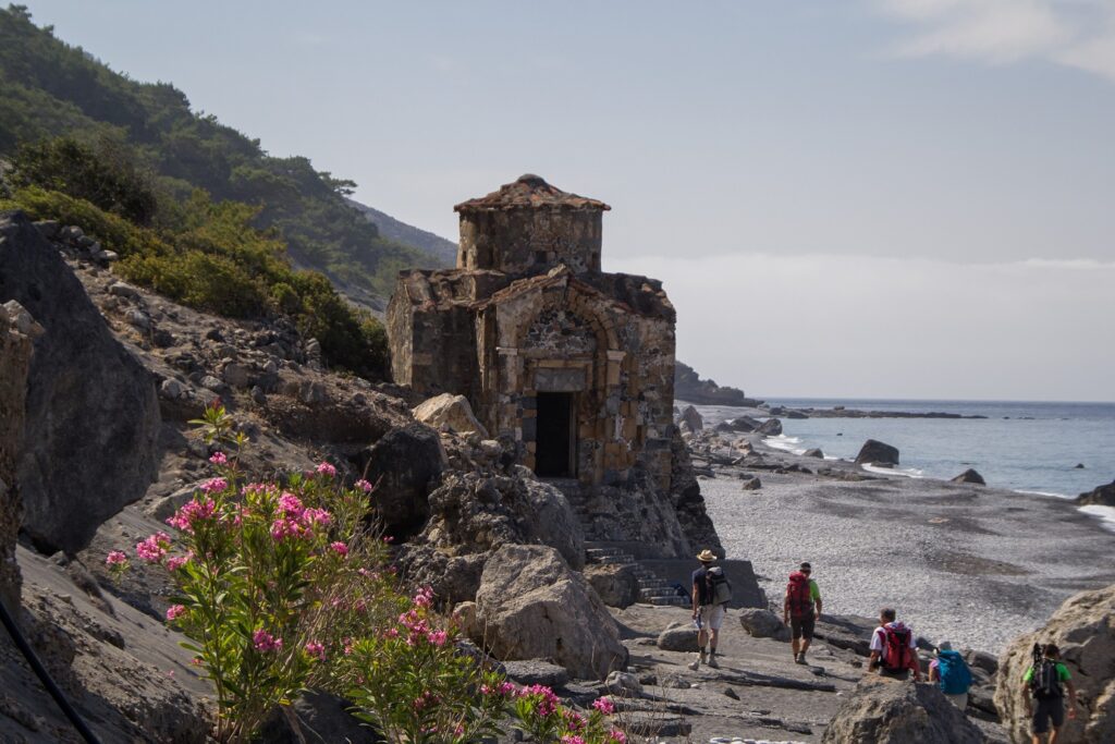 Paysage de plage en crête avec des randonneurs sur un sentier et une construction typique de l'île sur la gauche de l'image