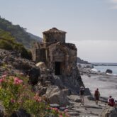 Paysage de plage en crête avec des randonneurs sur un sentier et une construction typique de l'île sur la gauche de l'image