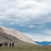Groupe de randonneurs avec leur guide en train de marcher en Mongolie avec un décor montagnard derrière