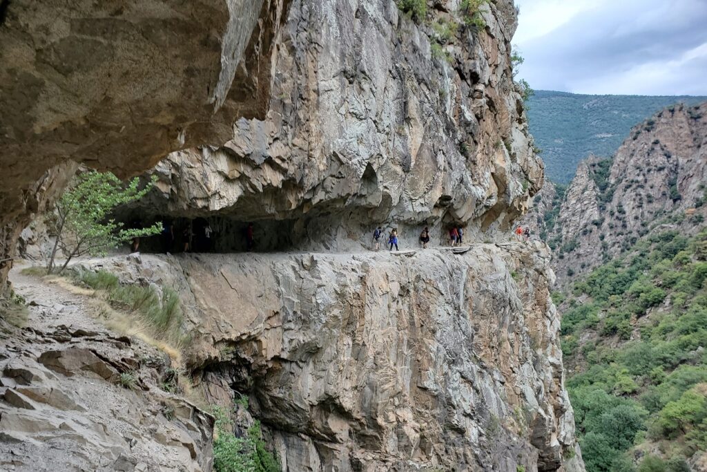 Groupe de randonneurs sur un sentier à flanc de montagne ancré dans la montagne