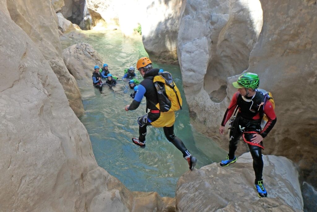 groupe de personnes en train de faire du canyoning avec leur guide, qui sautent dans l'eau dans un canyon en sierra de guara