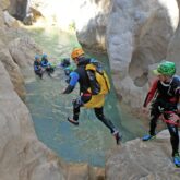groupe de personnes en train de faire du canyoning avec leur guide, qui sautent dans l'eau dans un canyon en sierra de guara