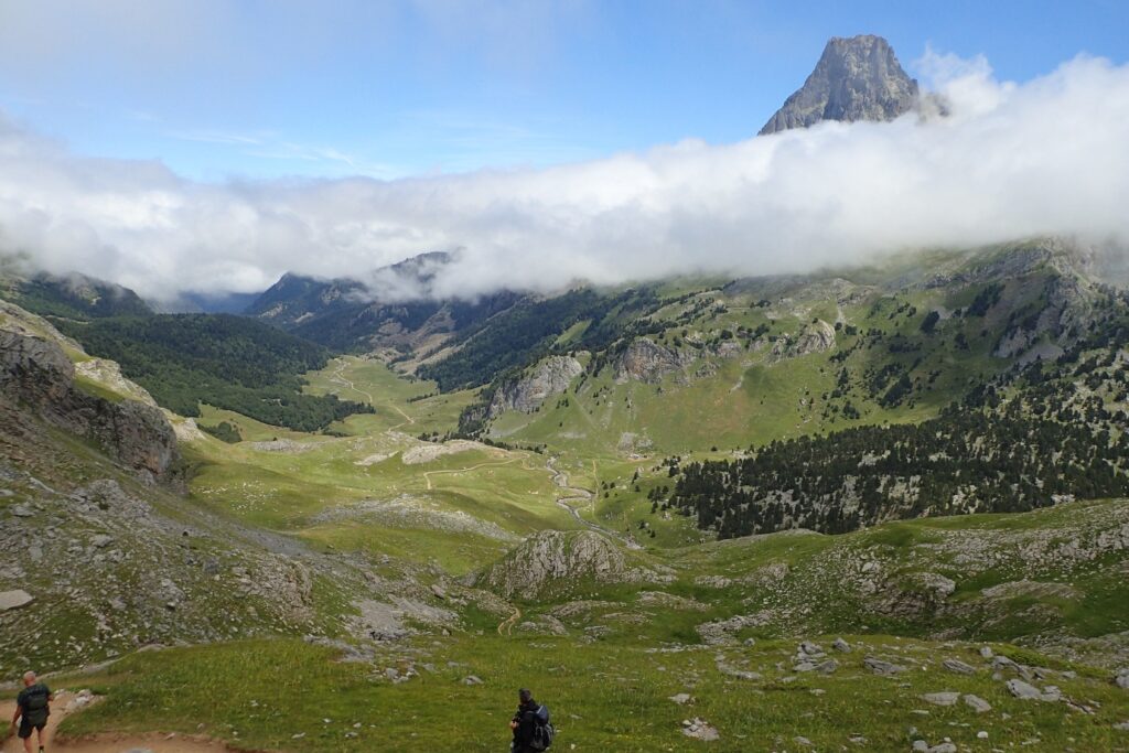 paysage de montagne avec des sentiers à travers la vallée et un groupe de randonneurs et leur guide qui descendent à flanc de la montagne dans les vallées d'Aspe et d'Ossau