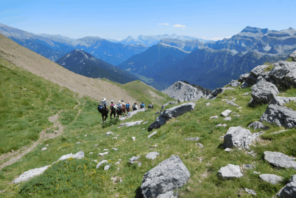 Groupe de randonneurs sur un sentier de montagne avec leur guide, et de nombreux sommets derrière eux sur le circuit Gavarnie Ordesa