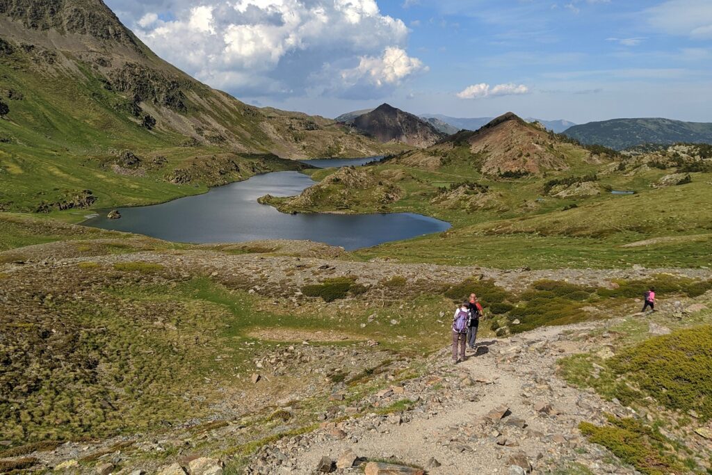Paysage de montagne avec une étendue d'eau au centre encadré de végétation et de sommets en fond