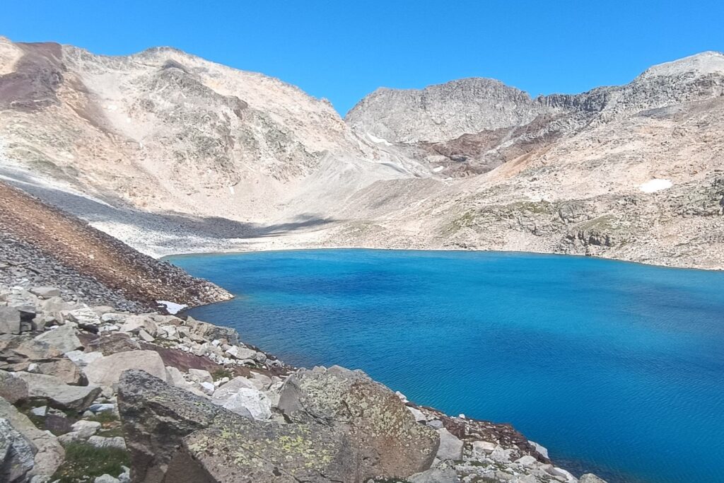 paysage de montagne avec un lac au centre de l'image et en fond des sommets enneigés