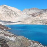 paysage de montagne avec un lac au centre de l'image et en fond des sommets enneigés