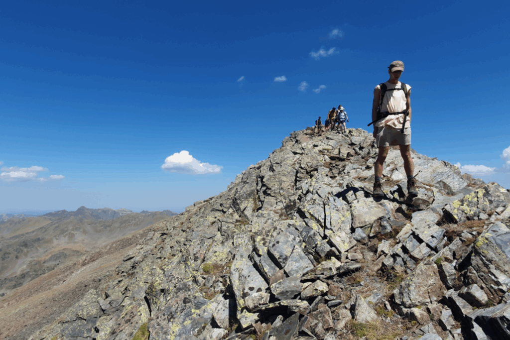 Groupe de randonneurs qui descendent d'un sommet surplommbé de roches grises