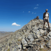 Groupe de randonneurs qui descendent d'un sommet surplommbé de roches grises