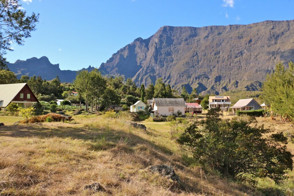 Paysage montagnard sur l'île de la Réunion avec au premier plan des champs et des maisons et à l'arrière-plan un sommet
