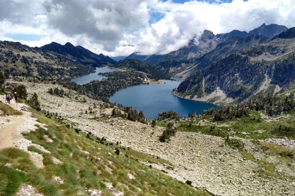 Paysage de montagne avec au premier plan un sentier de montagne, puis au second plan un lac et finalement des sommets au plus loin