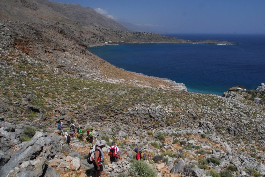 Groupe de randonneurs en Crète sur un sentier à flanc de montagne avec en contrebas la mer