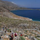 Groupe de randonneurs en Crète sur un sentier à flanc de montagne avec en contrebas la mer
