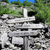 Panneau en bois indiquant les différents sentiers sur un chemin du GR10