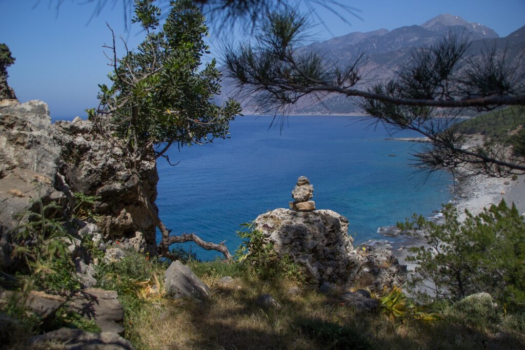 Paysage de Crète avec en contrebas la mer encadrée de montagnes, la prise de vue est faite depuis une montagne couverte d'arbres