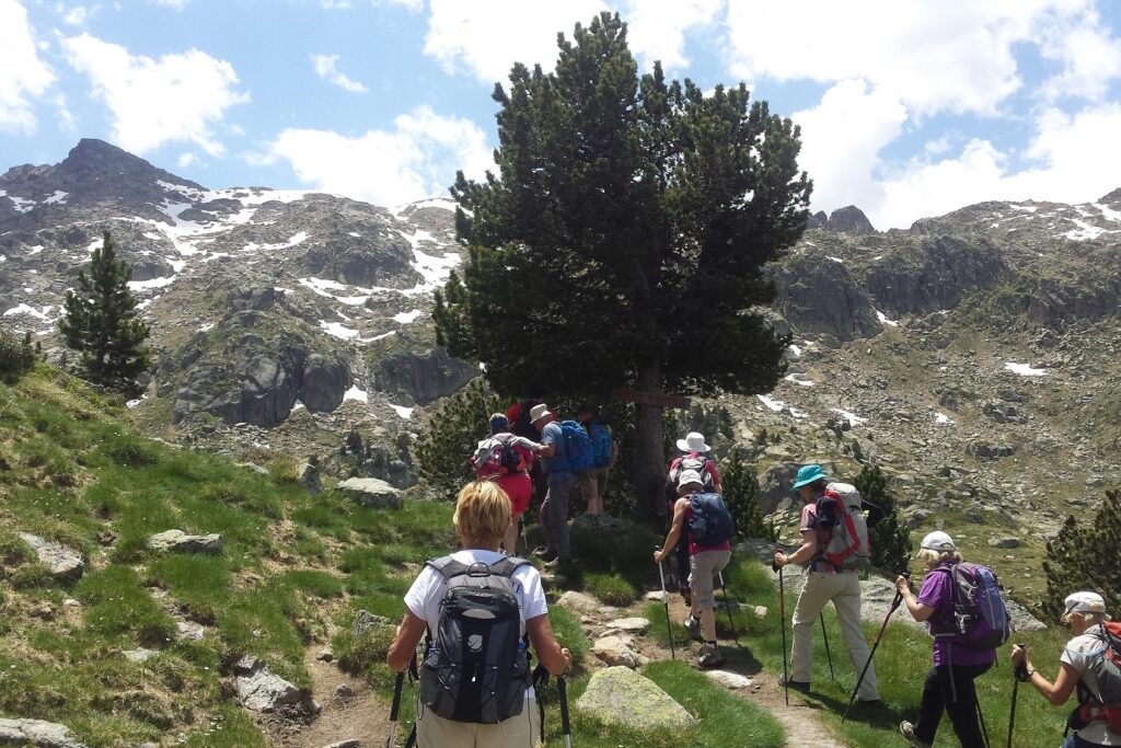 Groupe de randonneurs sur un sentier de randonnée aux abords d'un lac de montagne dans les Encantats