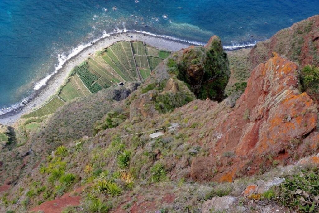 Prise de vue en hauteur depuis un sommet, en contrebas on voit une piste qui passe près de l'ocean