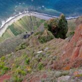 Prise de vue en hauteur depuis un sommet, en contrebas on voit une piste qui passe près de l'ocean