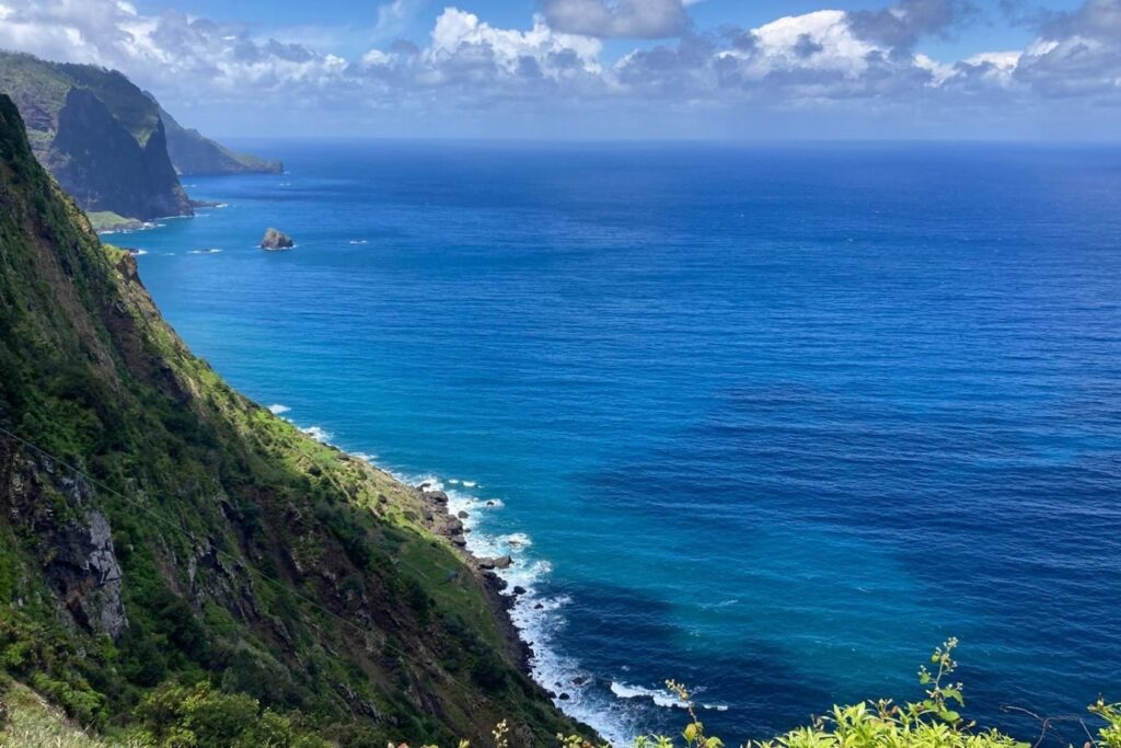 Paysage de bord d'océan avec vue sur l'eau turquoise et les montagnes de Madère qui se jettent dans l'eau sur la gauche