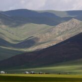 Paysage de montagne avec une plaine en bas, avec des yourtes et des chevaux
