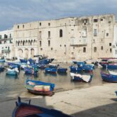 Paysage d'Italie avec un port contenant des bateaux et des monuments blancs comme dans le reste des Pouilles du sud