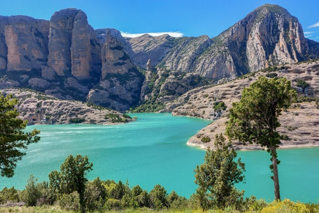 point de vue pris en recul, avec au premier plan des arbres, ensuite un rio qui forme comme un lac et finalement des sommets