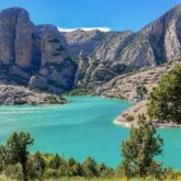 point de vue pris en recul, avec au premier plan des arbres, ensuite un rio qui forme comme un lac et finalement des sommets